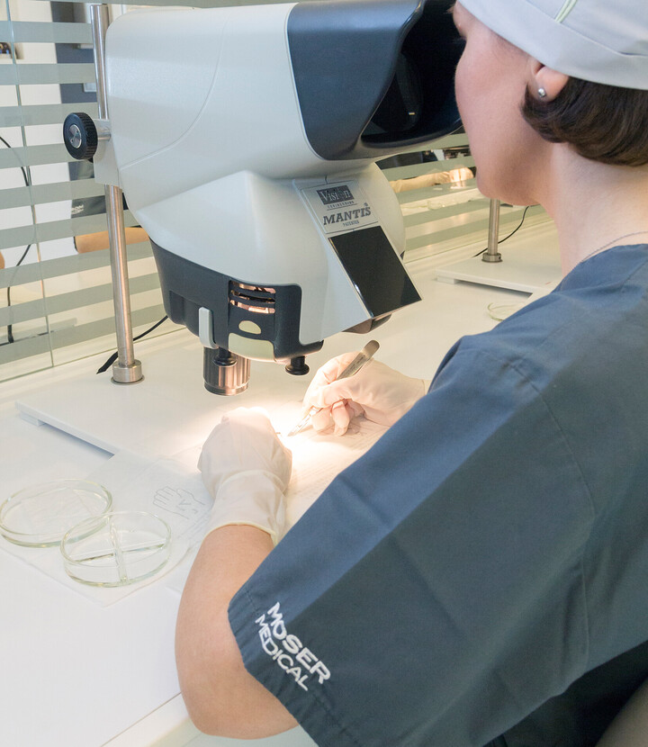 Mitarbeiterin von Moser Medical arbeitet an einem Mikroskop zur Haaranalyse