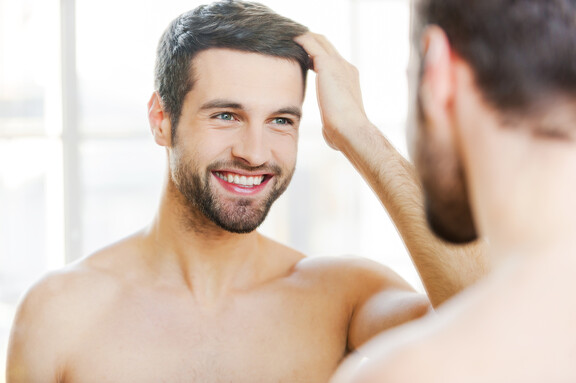 Mann bewundert seine volle Haarpracht nach der Moser-Methode gegen Haarausfall